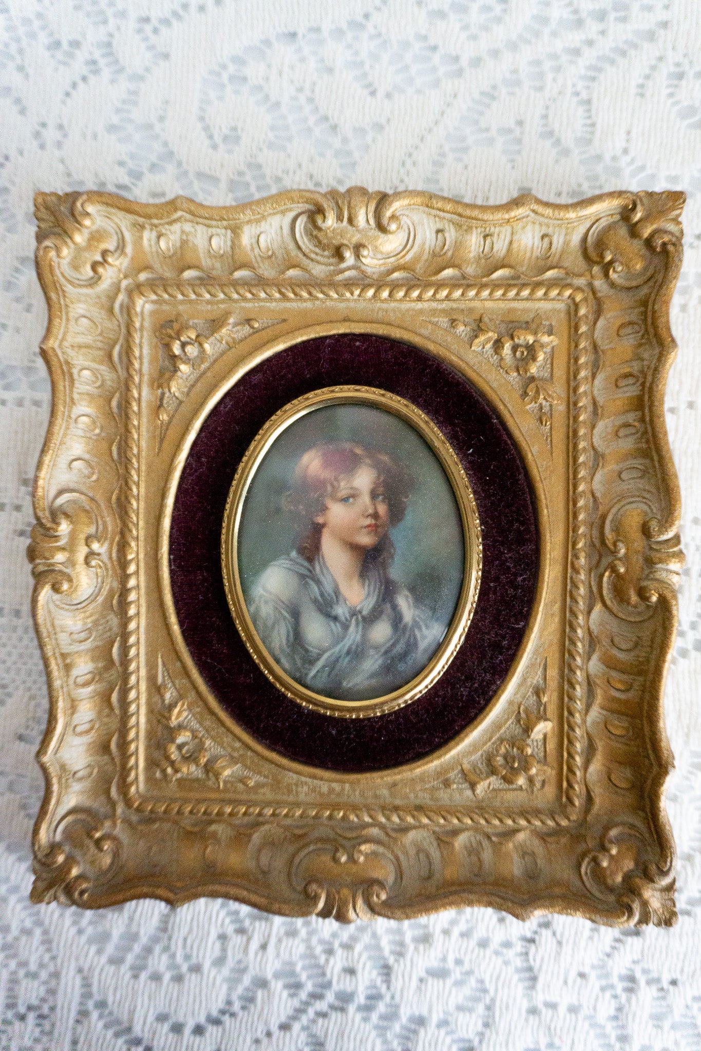 Cameo Creation wall art featuring 'Innocence' by Jean-Baptiste Greuze in an ornate gold frame with a burgundy velvet backdrop.