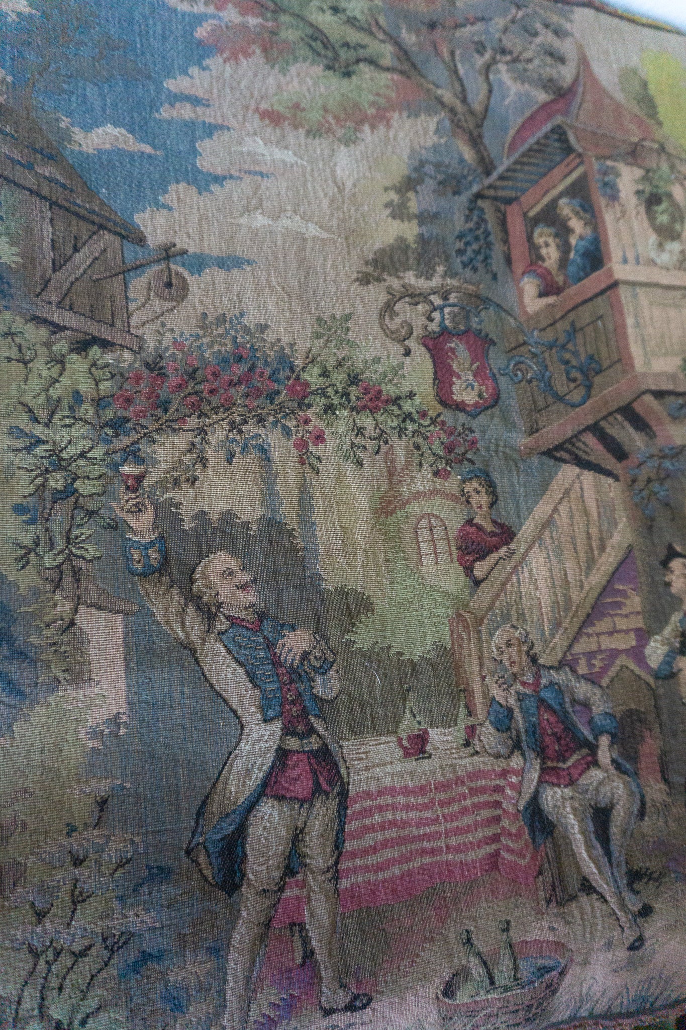 Close-up of the bottom left corner of the tapestry featuring a man raising a glass under a floral arbor.