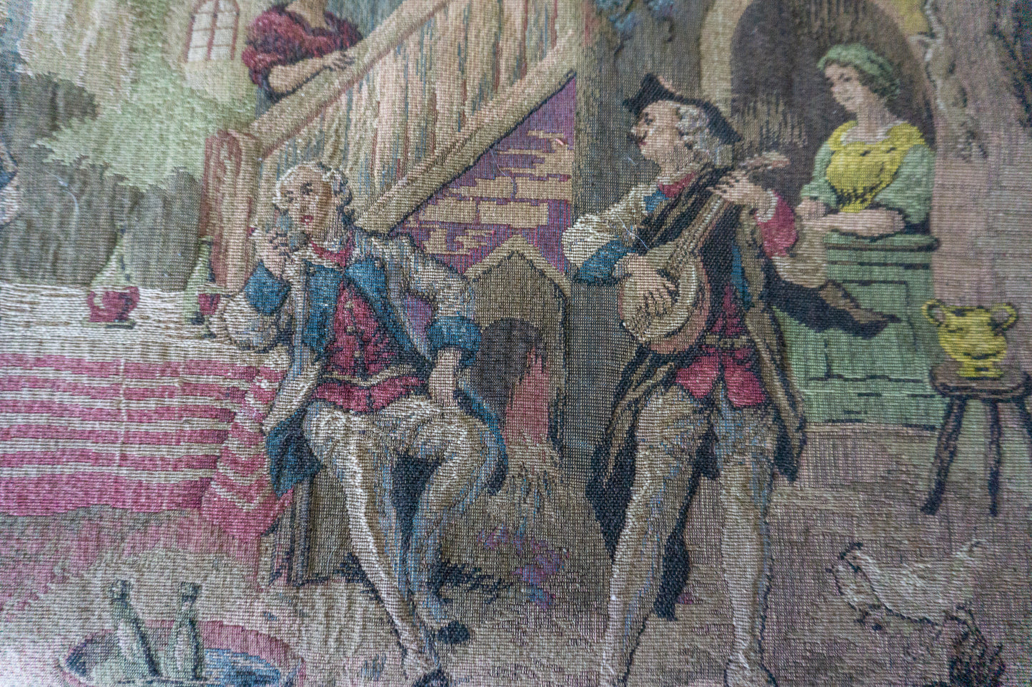 Close-up of the bottom right corner of the tapestry with musicians and a woman standing by a doorway.