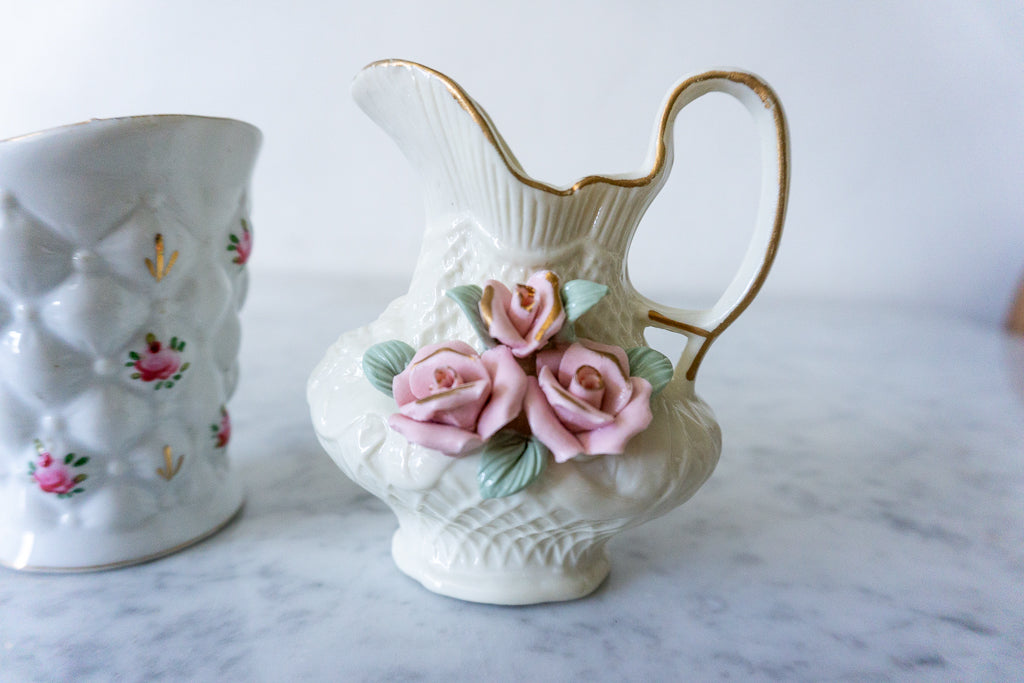 Side view of both floral pitchers displaying intricate details
