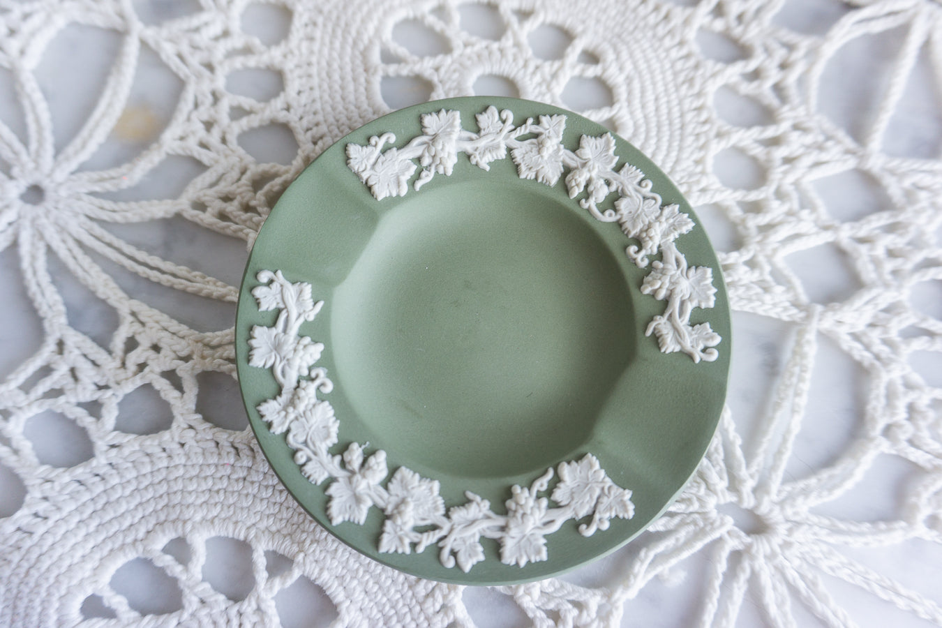 Wedgwood green Jasperware ashtray with white grapevine relief, displayed on a vintage lace doily for classic cottage decor style.
