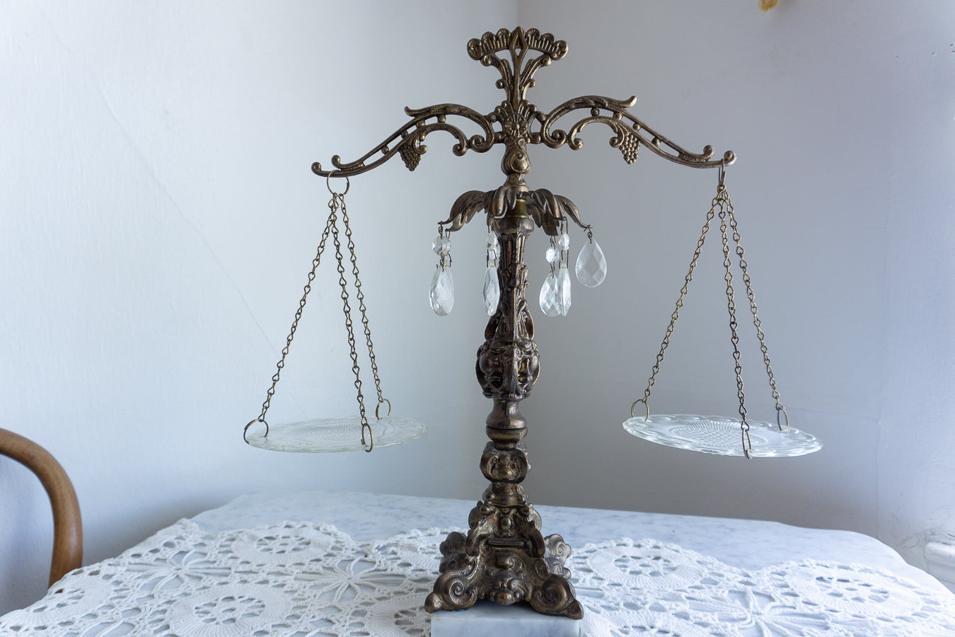 Vintage Hollywood Regency decorative Scales of Justice with crystal prisms, etched glass dishes, ornate cast metal detailing, and a white marble base — styled on a lace-covered marble tabletop