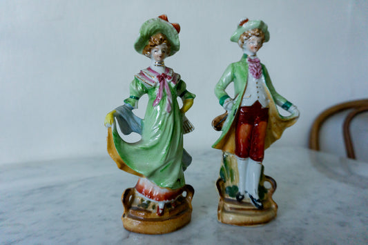 Victorian-style porcelain figurines of a lady and gentleman.