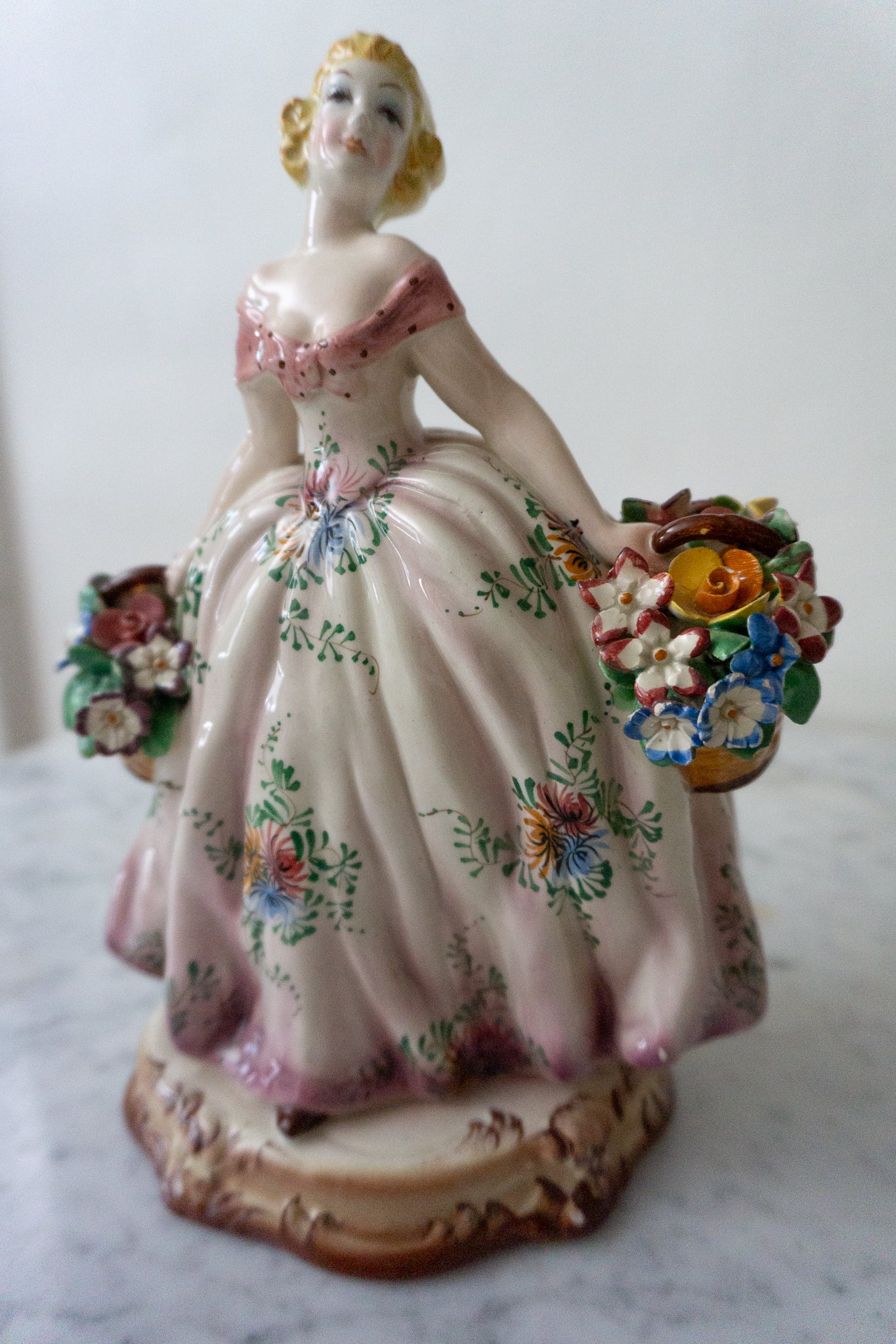 Side view of the porcelain lady figurine showing detailed flower baskets.