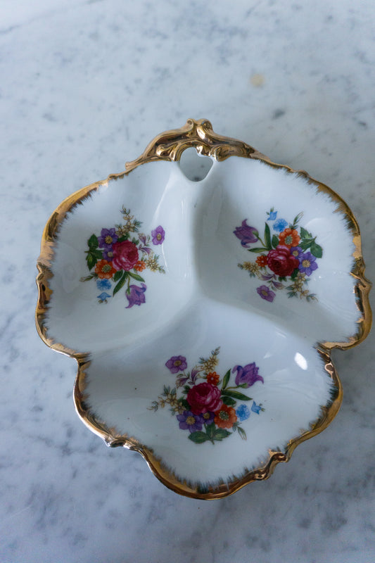 Top view of a vintage decorative porcelain dish with floral design and gold trim.