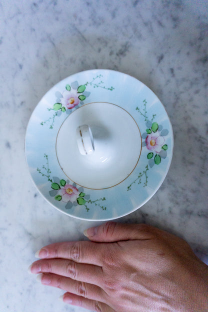 Vintage hand-painted porcelain lemon slice server on a marble surface, with a hand for scale.