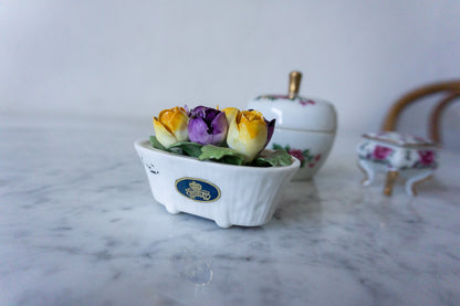 Porcelain flower arrangement with purple and yellow flowers.