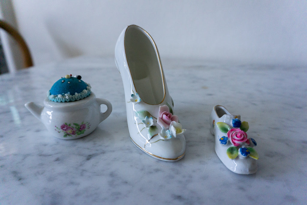 Collection of porcelain miniatures including a shoe, slipper, and teapot pincushion