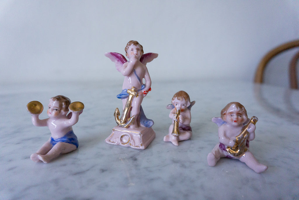 Close-up of four hand-painted Japanese ceramic cherub figurines, each playing a different musical instrument.