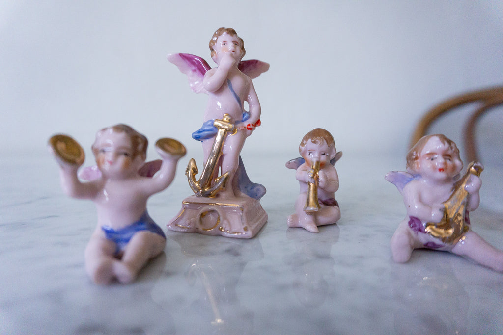 Set of four mcm ceramic cherub figurines with vibrant colors and detailed craftsmanship, made in Japan.