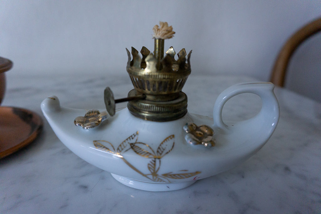 White porcelain miniature lamp with gold accents and glass chimney on a marble surface.