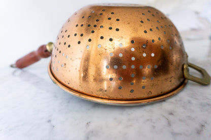 Copper colander with patina and wooden handle.