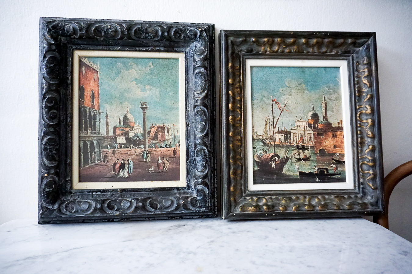 Pair of framed antique Italian Venetian lithographs displayed on a marble surface.