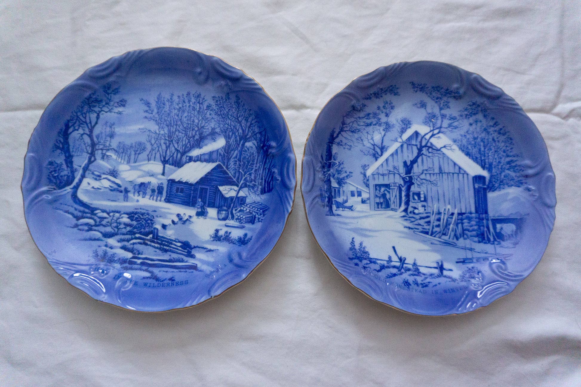 Set of 2 blue and white plates with intricate winter landscape designs.